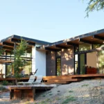 Mid-Century Modern house exterior in California with large glass windows and open deck surrounded by nature.