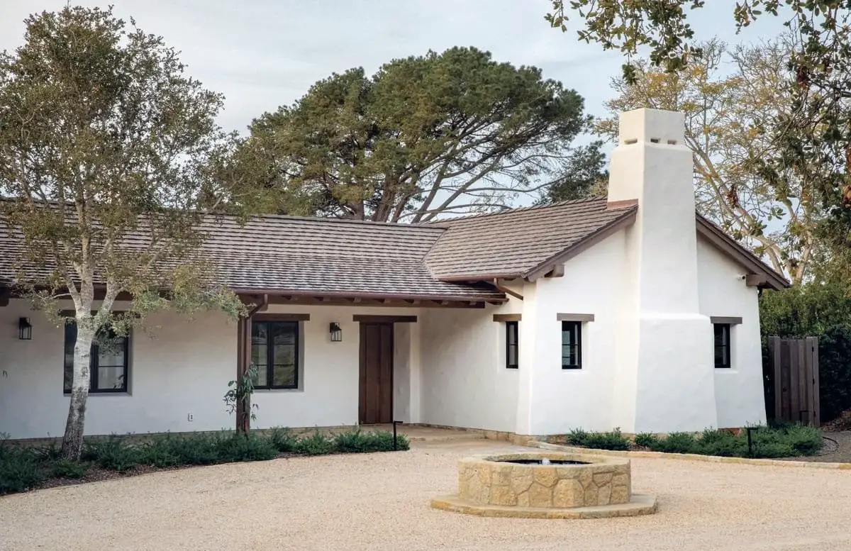 Single-story California Ranch style home with white stucco walls, wooden accents, and a central courtyard fountain.