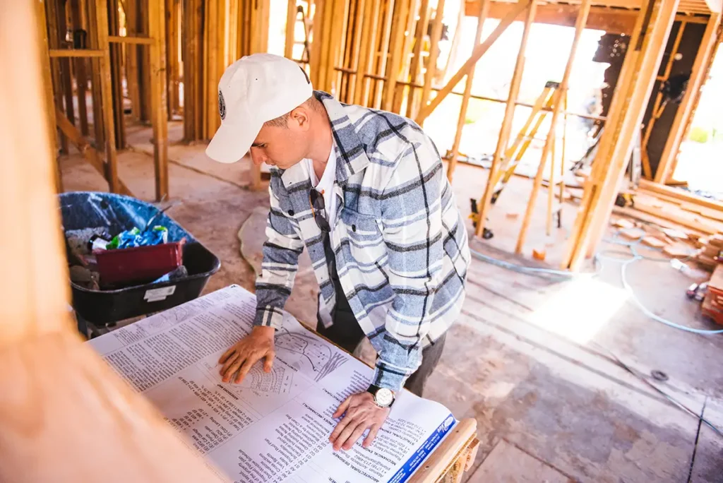 Builder reviewing architectural plans during home construction