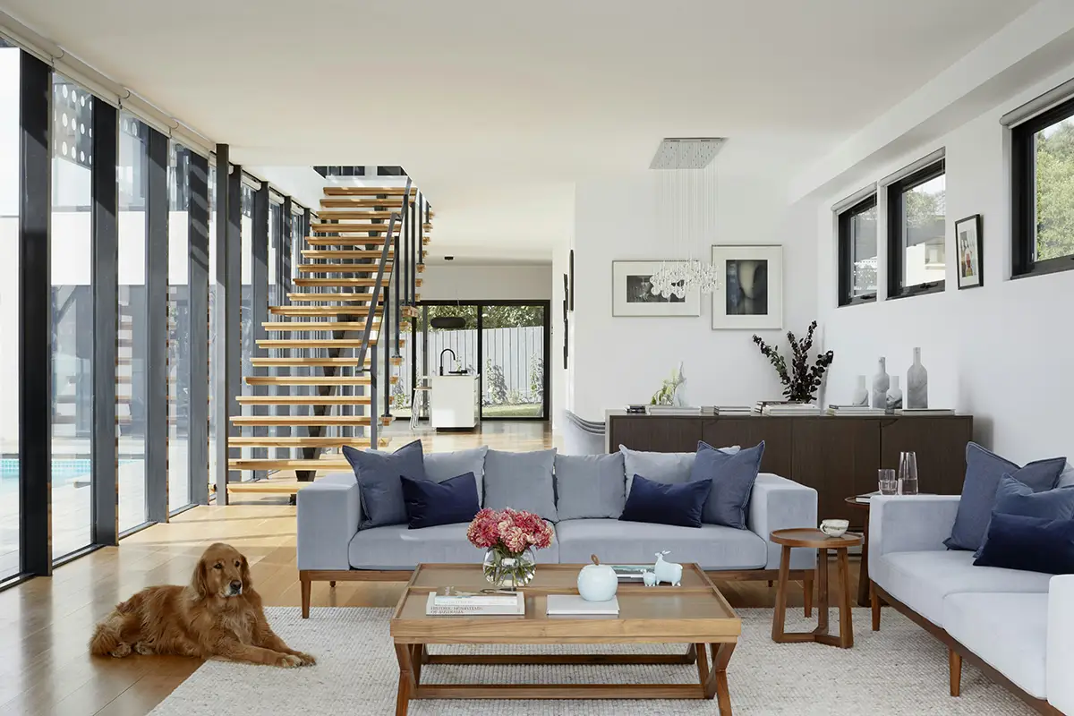modern open living room with glass wall room addition and staircase