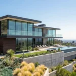 Modern hillside home with glass facade and infinity pool overlooking the city