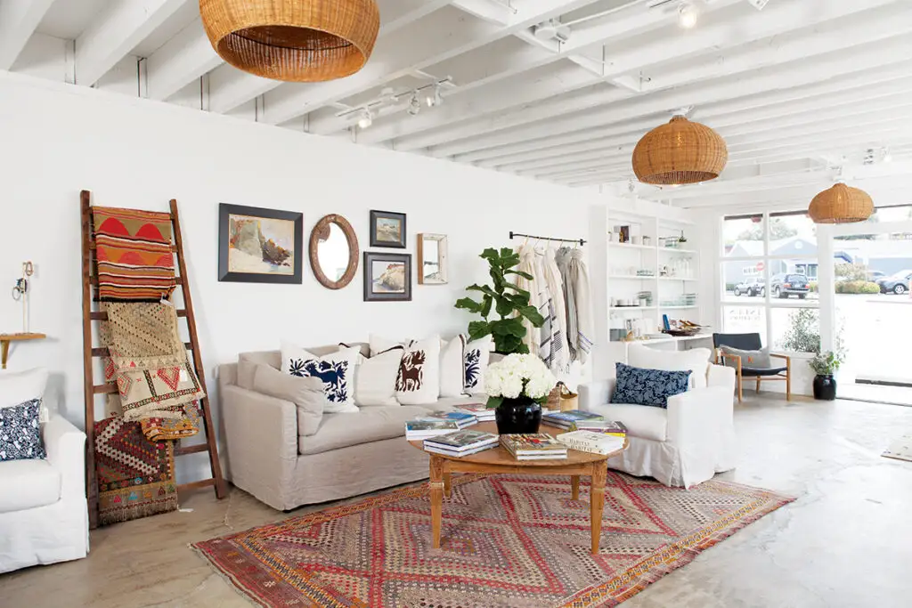 Coastal living room interior with woven pendants, patterned rug, and neutral sofas