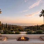 Luxury outdoor terrace with fire pit, built-in seating, and panoramic ocean view at sunset